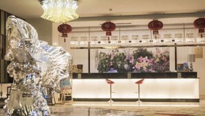 Un espace d’accueil au design moderne, agrémenté d’une grande sculpture abstraite, d’un comptoir bien éclairé et de lanternes rouges traditionnelles.