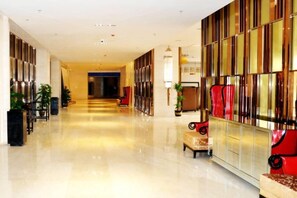 A hotel lobby with a long corridor, seating areas, and a reception desk.