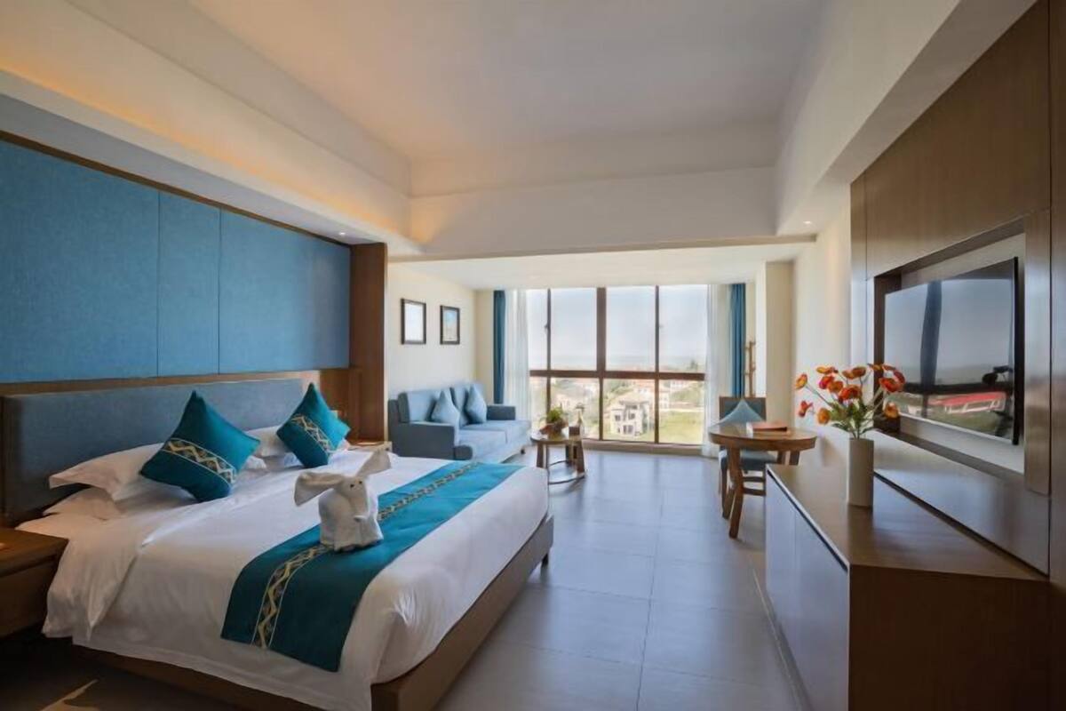 Een moderne hotelkamer met een groot bed, een bank, een televisie en een balkon met uitzicht.