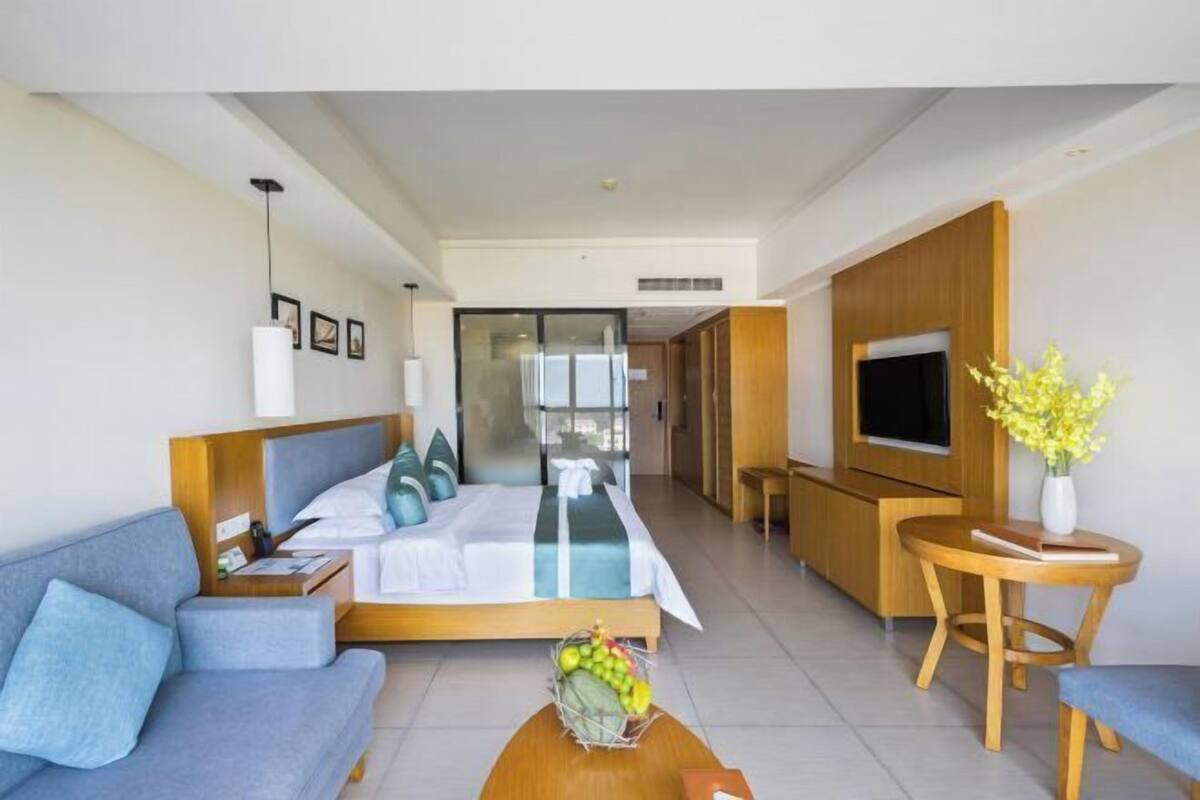 Een moderne hotelkamer met een bed, bank, televisie en een eethoek.