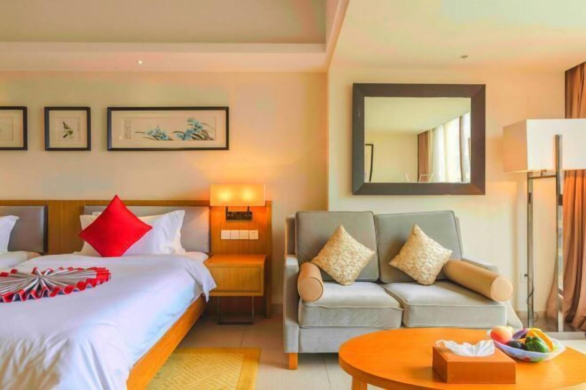 Een hotelkamer met een bed, een bank, een bijzettafeltje en een spiegel.