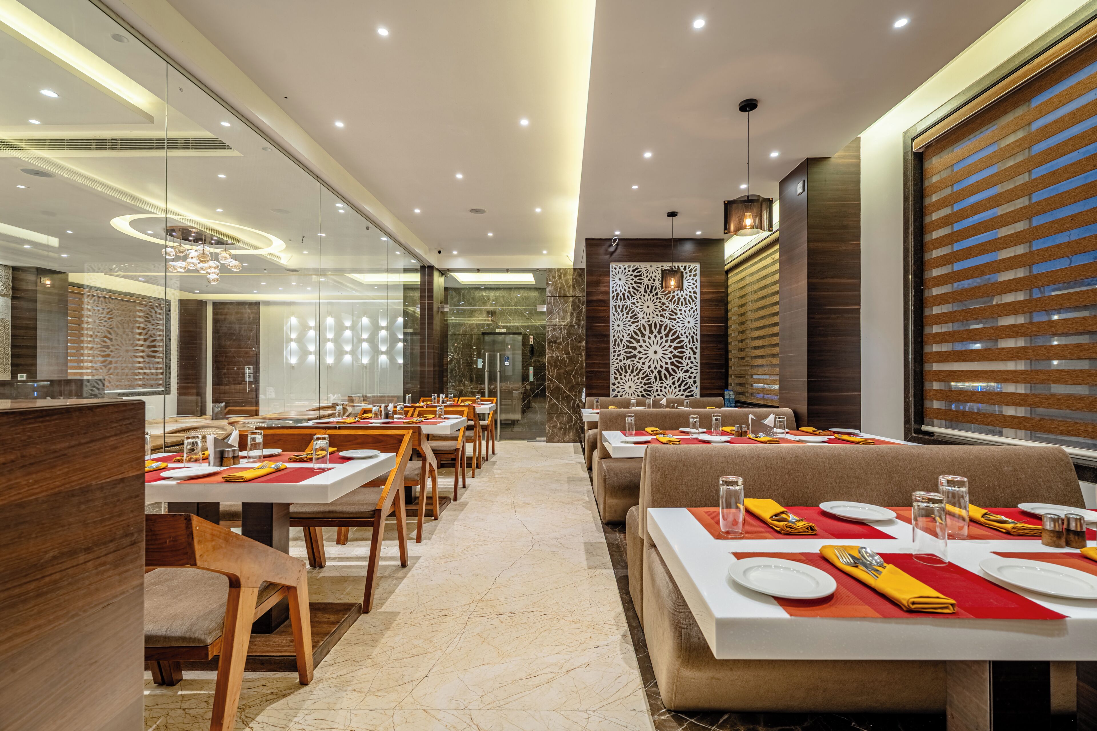 A modern restaurant with glass partitions, wooden furniture, and a patterned wall.