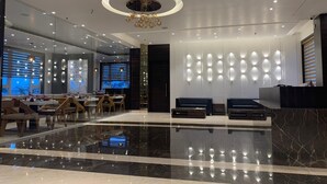 A modern lobby with a marble floor, a reception desk, seating area, and a dining section with tables and chairs. - Econest Hotel (Rampurhat)