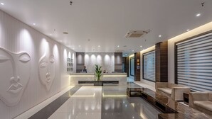 A modern reception area with a marble reception desk, a seating area with sofas, and a decorative wall with abstract designs. - Econest Hotel (Rampurhat)