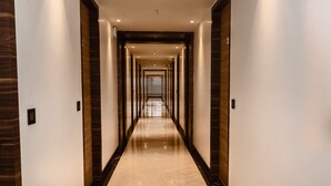 A long, narrow hallway with a polished marble floor and dark wooden paneling on the walls. - Econest Hotel (Rampurhat)