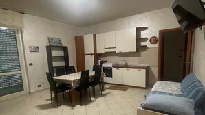 Ein kompakter Wohnraum mit Essbereich, Küchenzeile und Bett.