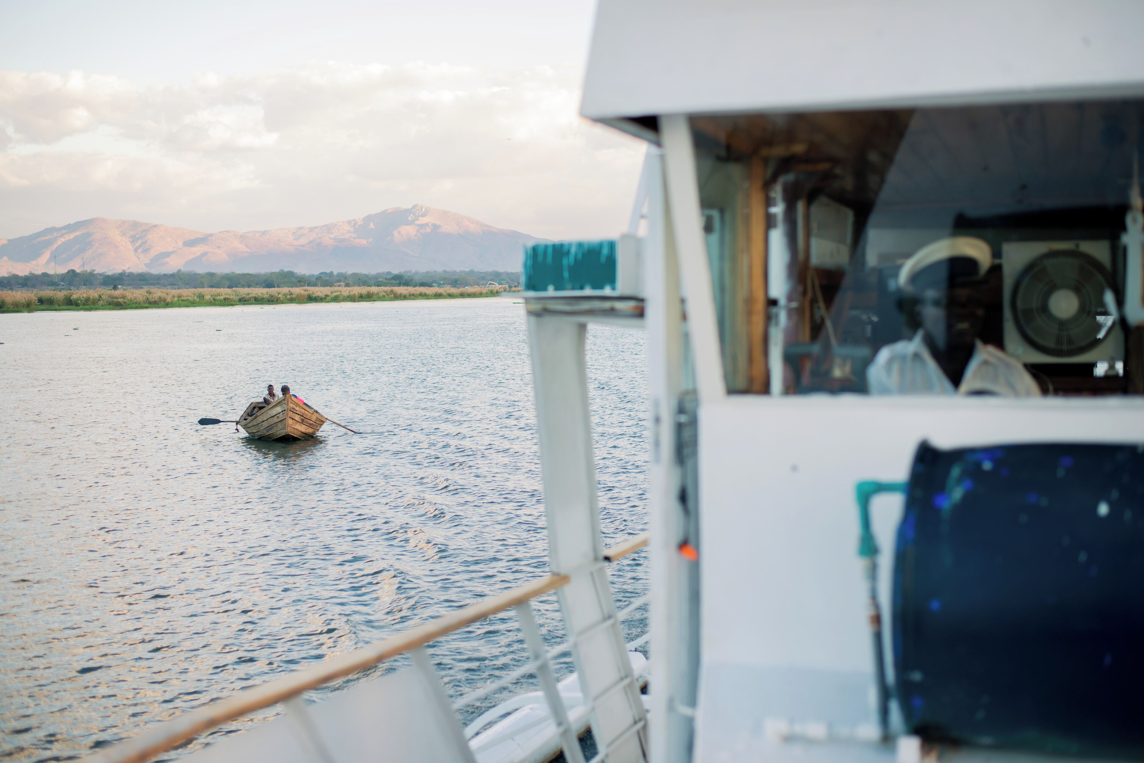 A boat on calm water with a mountain in the background.