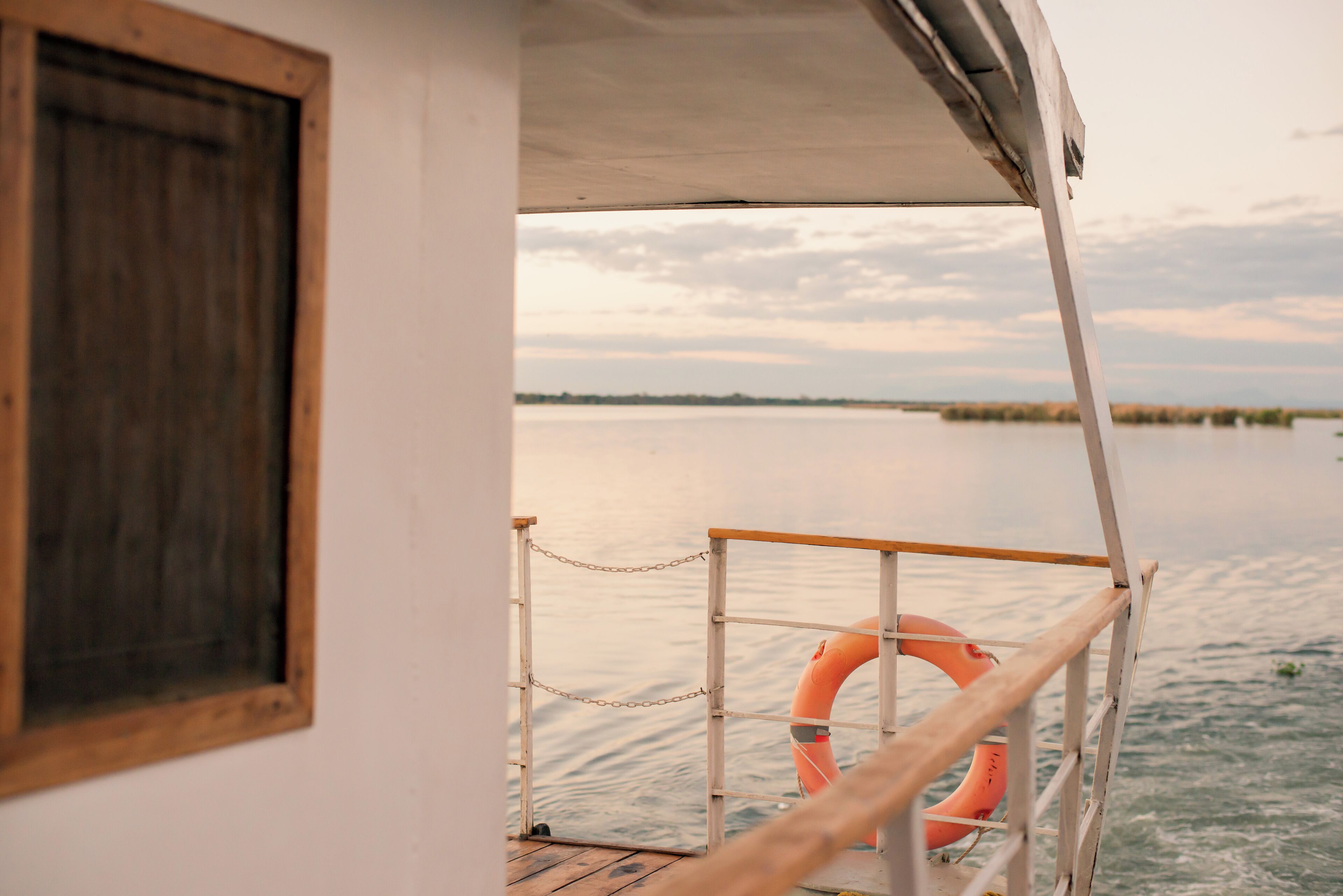 A boat's deck with a lifebuoy, a chain, and a wooden railing.
