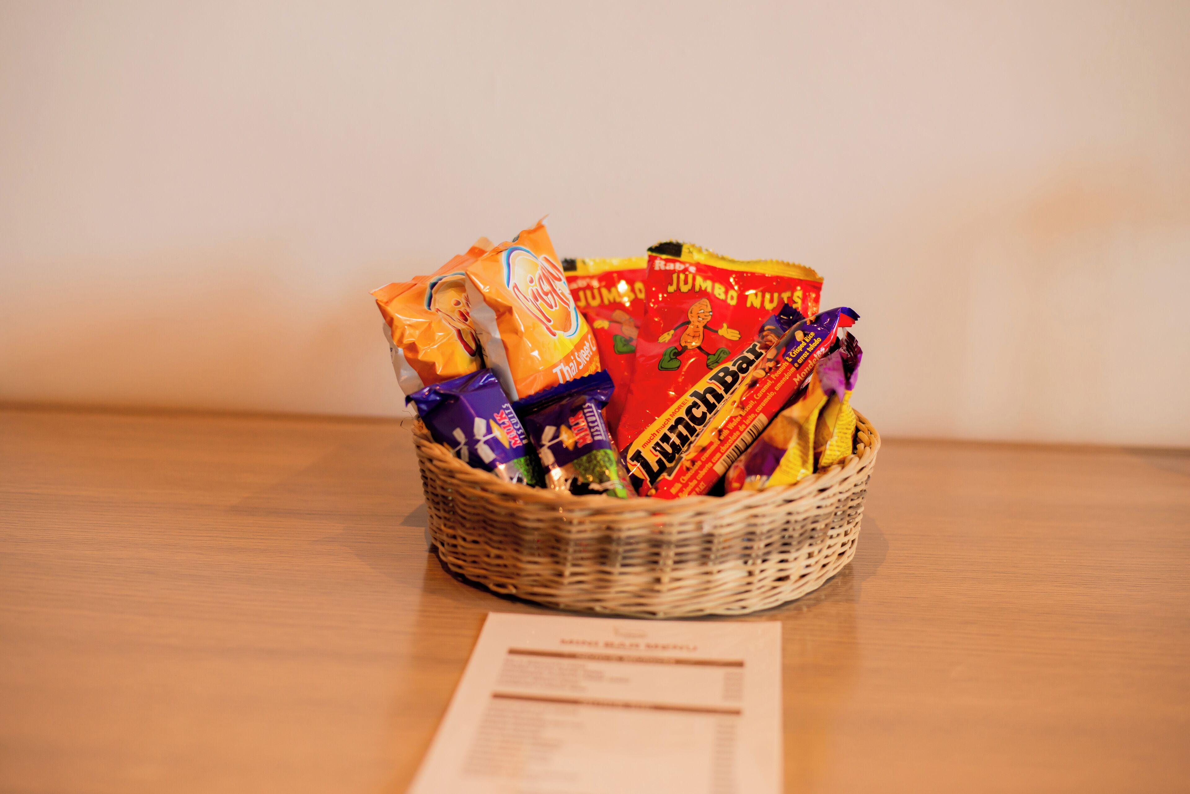 A wicker basket filled with assorted snacks on a wooden table.
