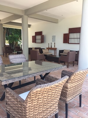 Relax in a sheltered outdoor seating area with a glass-top table and wicker chairs.
