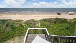 Una terraza de madera que da a una playa con vista al océano y dunas.