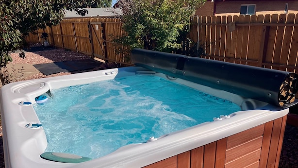 A hot tub with a wooden exterior and a white interior, surrounded by a wooden fence and trees. - Hot Tub Cozy Cottage in Colorado Springs (Colorado Springs)