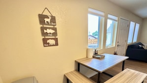 A dining area with a wooden table and benches, a trash can, and a wall-mounted sign with animal silhouettes. - Hot Tub Cozy Cottage in Colorado Springs (Colorado Springs)