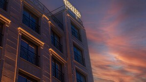 A hotel with a prominent sign on the top, multiple windows, and a balcony with iron railings. - Monalisa (Kusadasi)