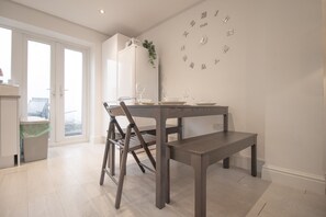Ein Essbereich mit Holztisch und -stühlen, einer Wanduhr und einem Fenster mit Blick.