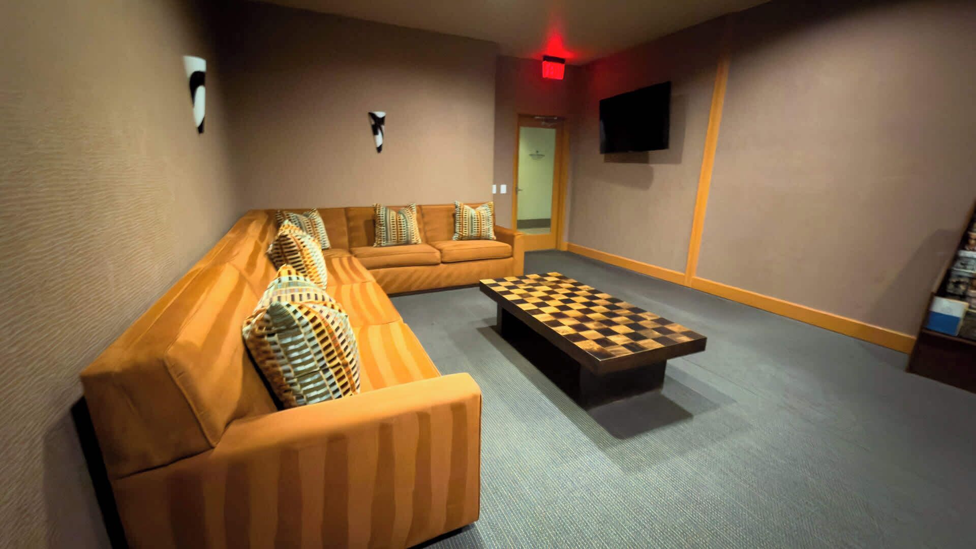 Ein Wohnzimmer mit einer Eckcouch, einem Couchtisch und einem flachbildfernseher an der Wand.