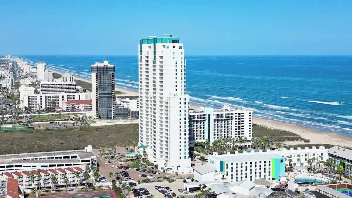 A coastal hotel with multiple buildings, a beach, and a view of the ocean.