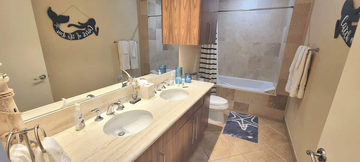 A modern bathroom with two sinks, a large mirror, and a shower area.