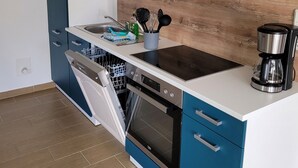 A modern kitchen with white and blue cabinetry, a stainless steel dishwasher, an oven, and a coffee maker on the countertop.