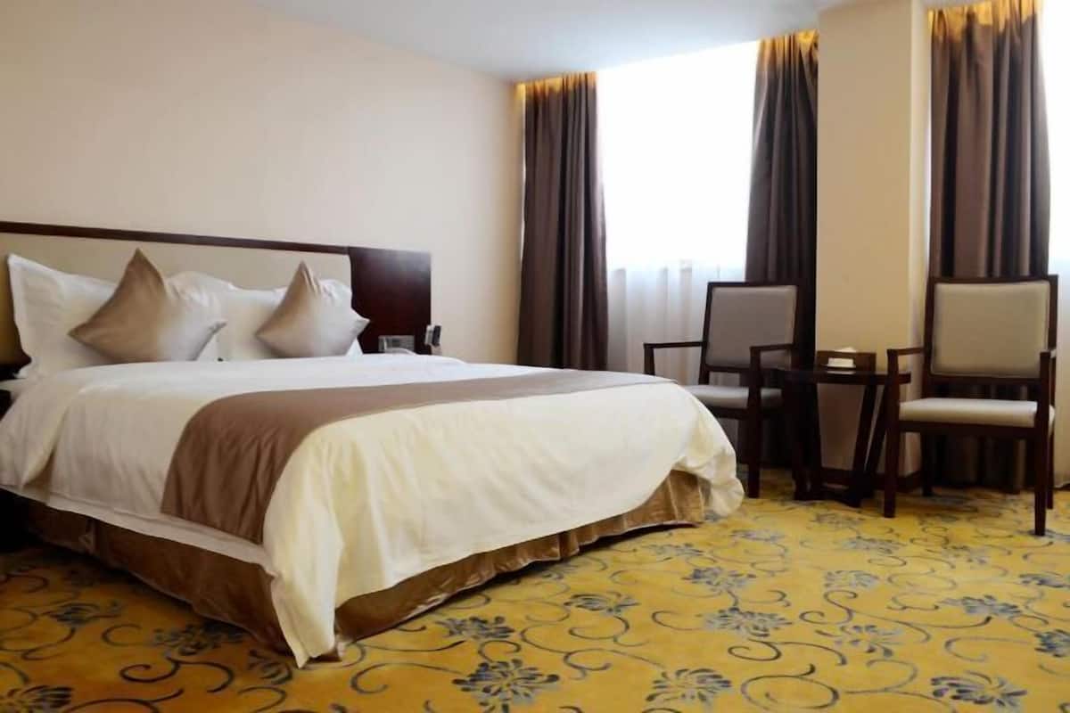 A hotel room with a bed, a desk, and a chair.