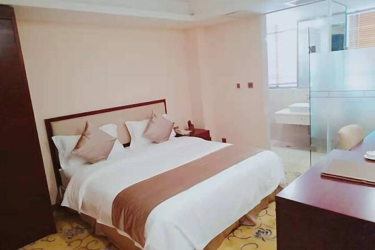A hotel room with a bed, bedside table, and a desk with a chair.