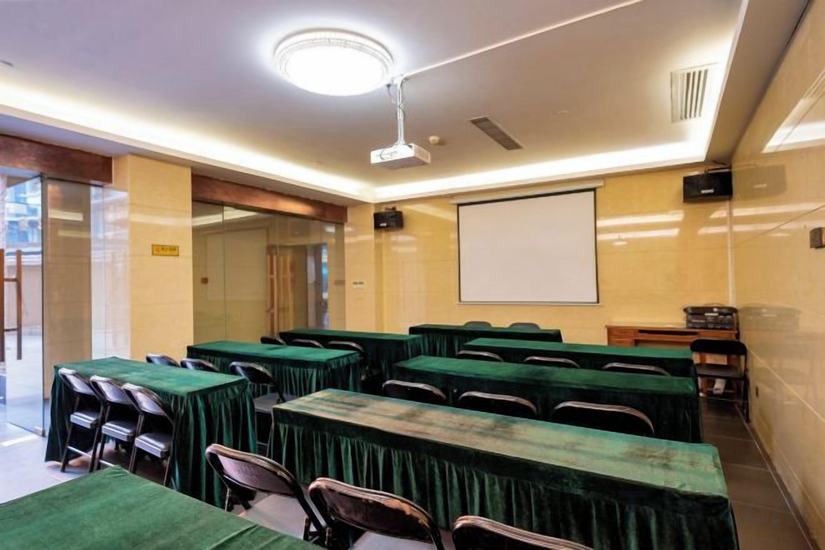 A conference room with tables and chairs, a projector screen, and a whiteboard.