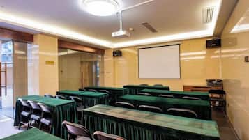 A conference room with tables and chairs, a projector screen, and a whiteboard.