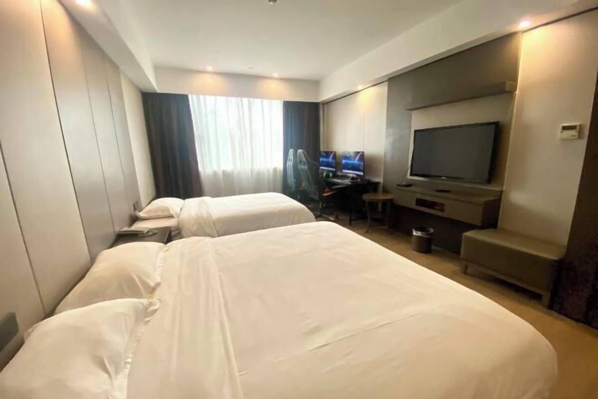 Une chambre d’hôtel avec deux lits, un bureau, une télévision et un coin salon.
