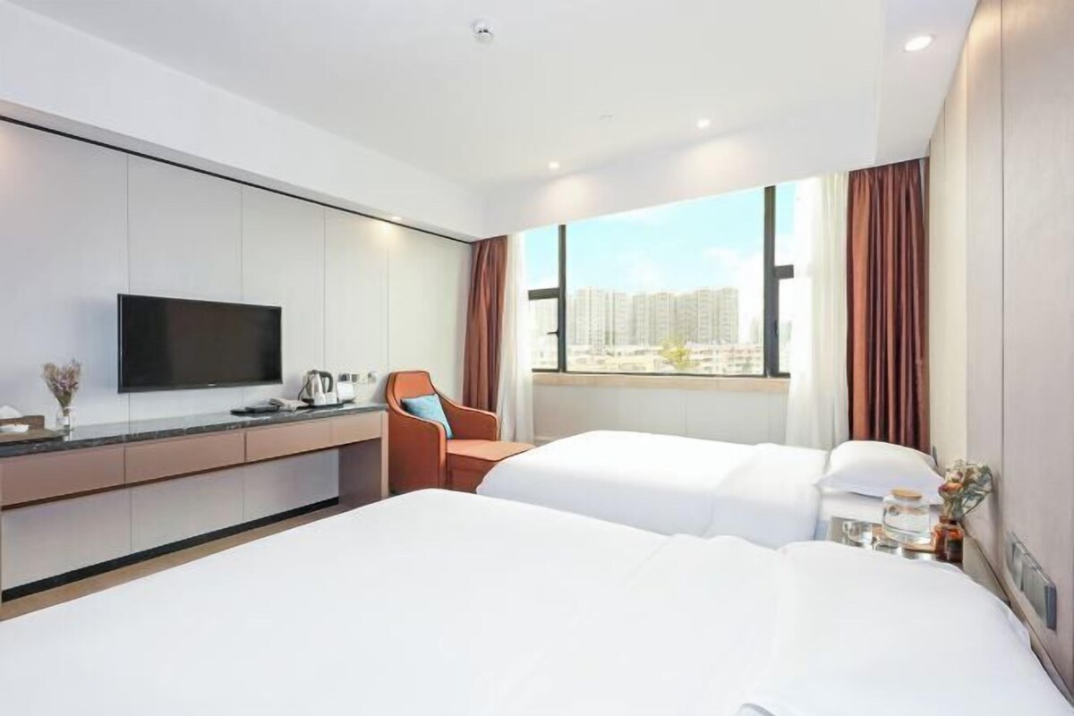 Een hotelkamer met twee bedden, een televisie, een bureau en een raam met uitzicht over de stad.