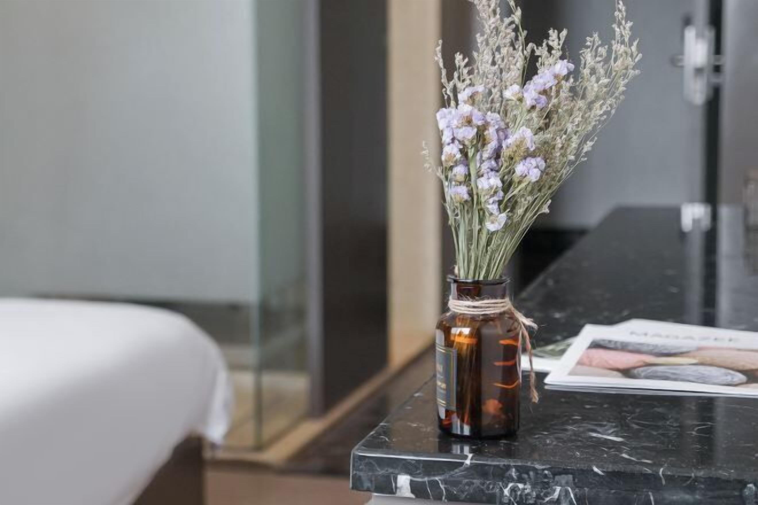 A marble countertop with a small vase containing lavender flowers.