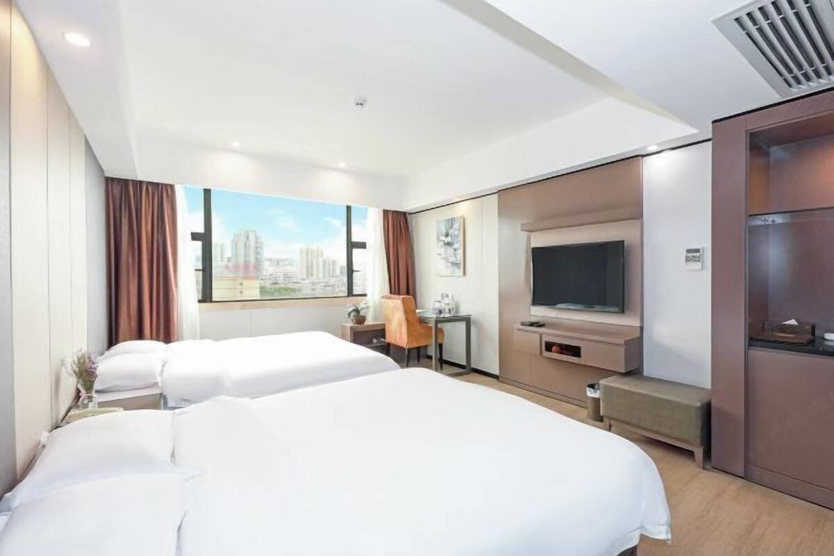 Une chambre d’hôtel avec deux lits, un bureau, une télévision et une vue sur la ville.