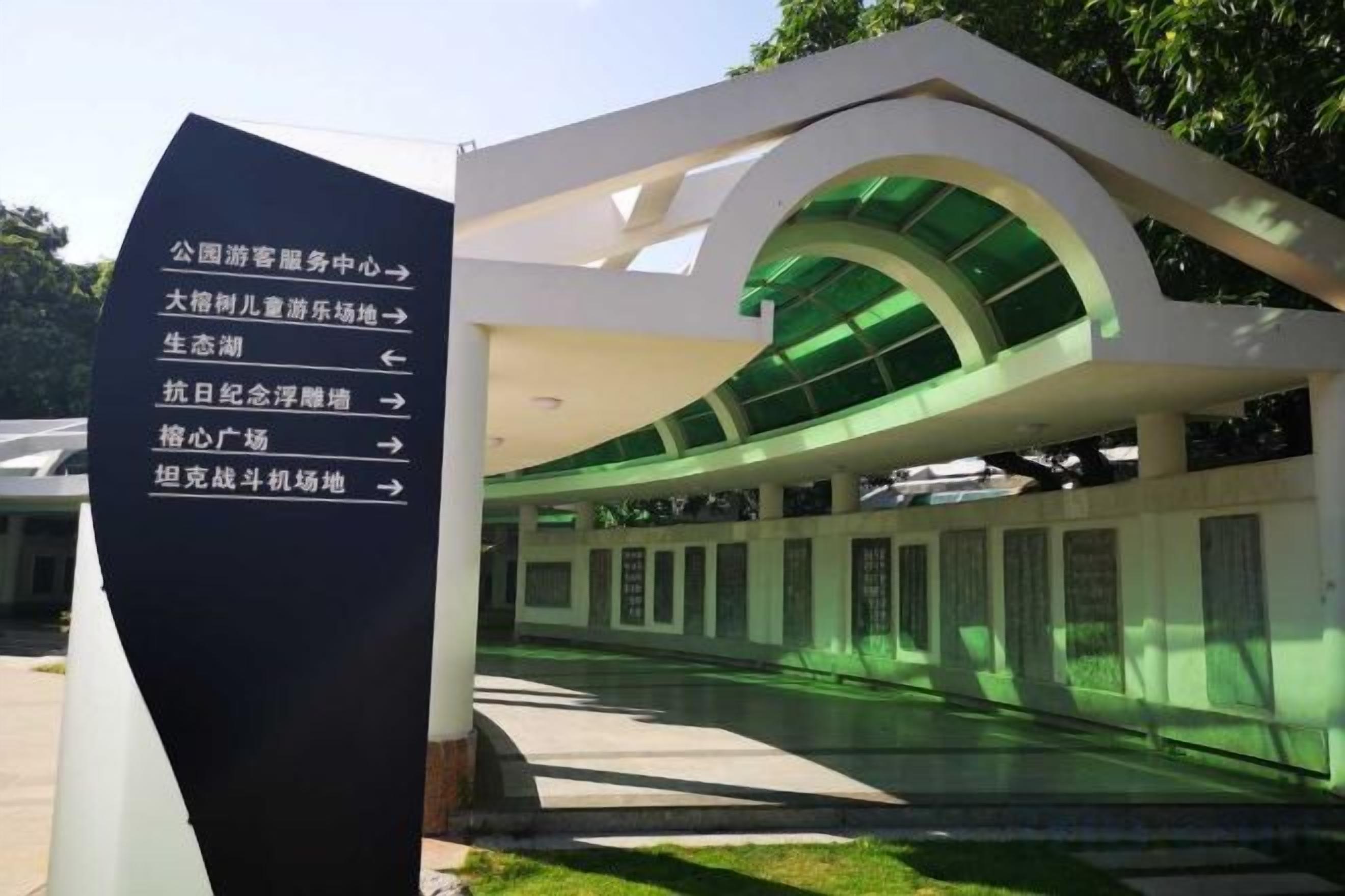 A modern architectural structure with a curved glass roof and a directional sign indicating various facilities.