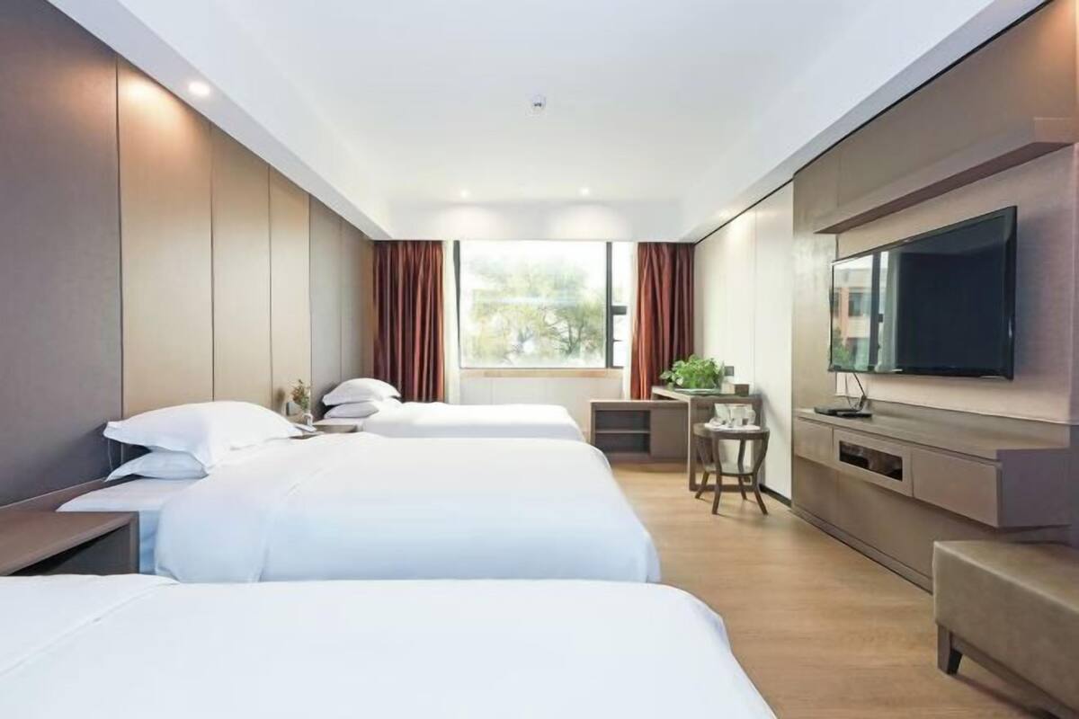 Une chambre d’hôtel moderne équipée de deux lits, d’une télévision, d’un bureau et d’une fenêtre avec des rideaux.