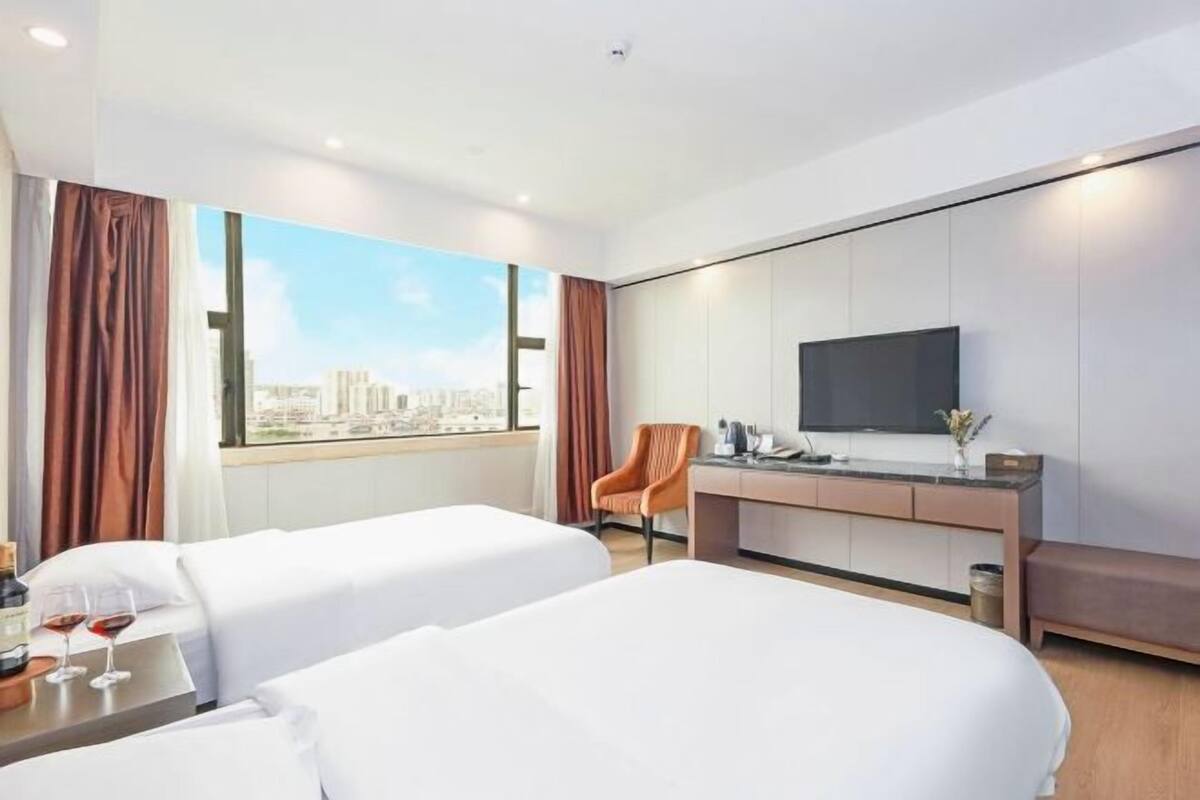 Une chambre d’hôtel avec deux lits, un bureau, une chaise et un téléviseur.
