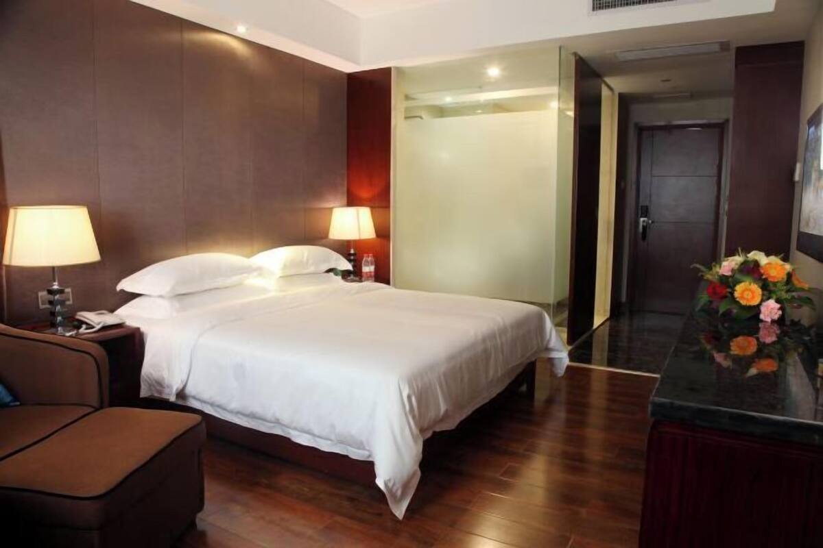 Une chambre d’hôtel avec un lit, des lampes de chevet, un bureau et une chaise.