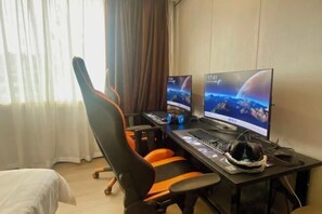 A hotel room with a gaming desk, two monitors, a keyboard, and a gaming chair. - Yiguo Fengqing Holiday Hotel (Beihai Beibu Gulf Plaza Park Road Branch) (Beihai)