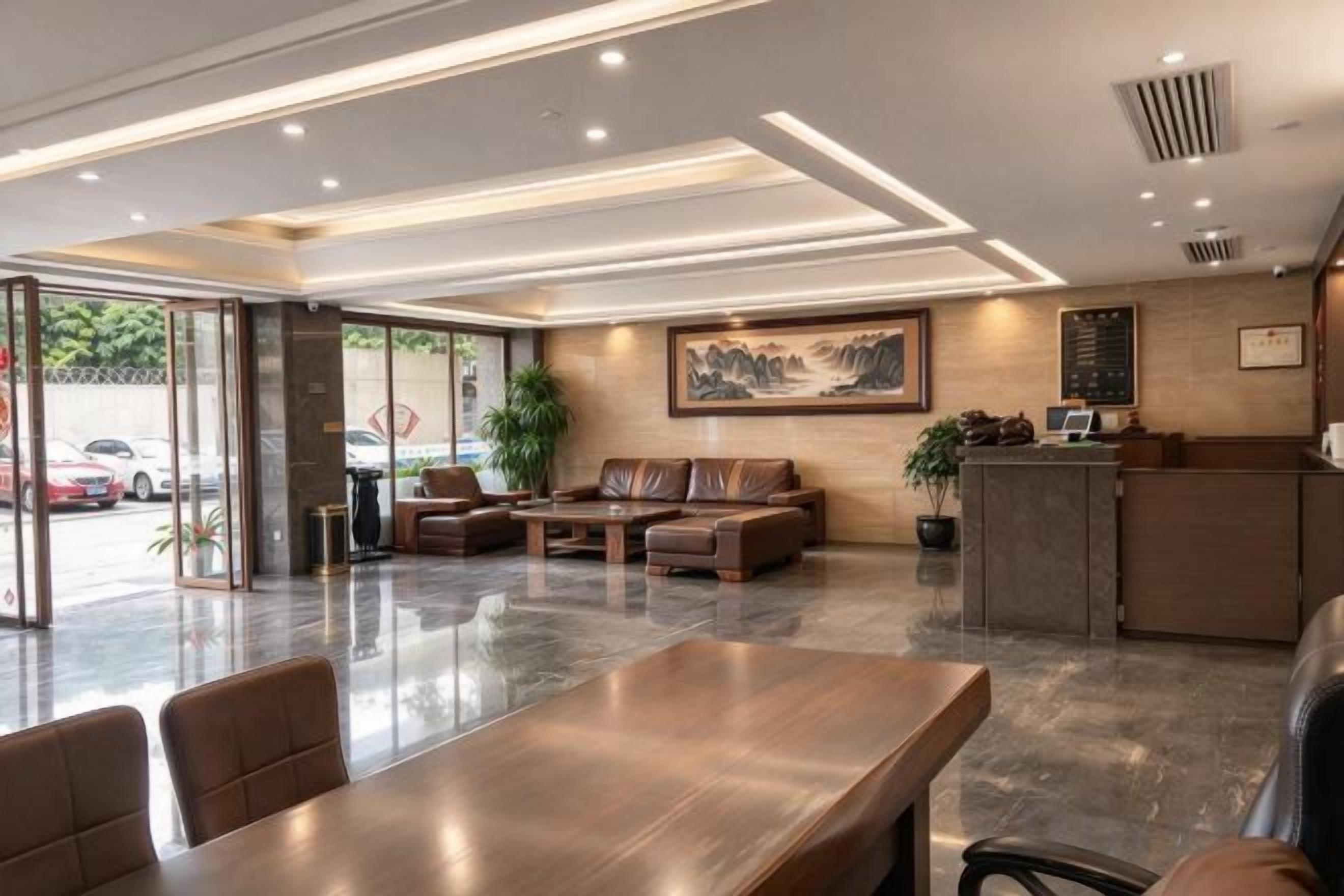 A hotel lobby with a reception desk, seating area, and a large dining table.