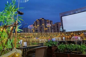 Un espacio de comedor al aire libre con mesas, sillas y plantas.