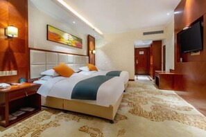 A hotel room with a large bed, a bedside table, a TV, and a carpeted floor.
