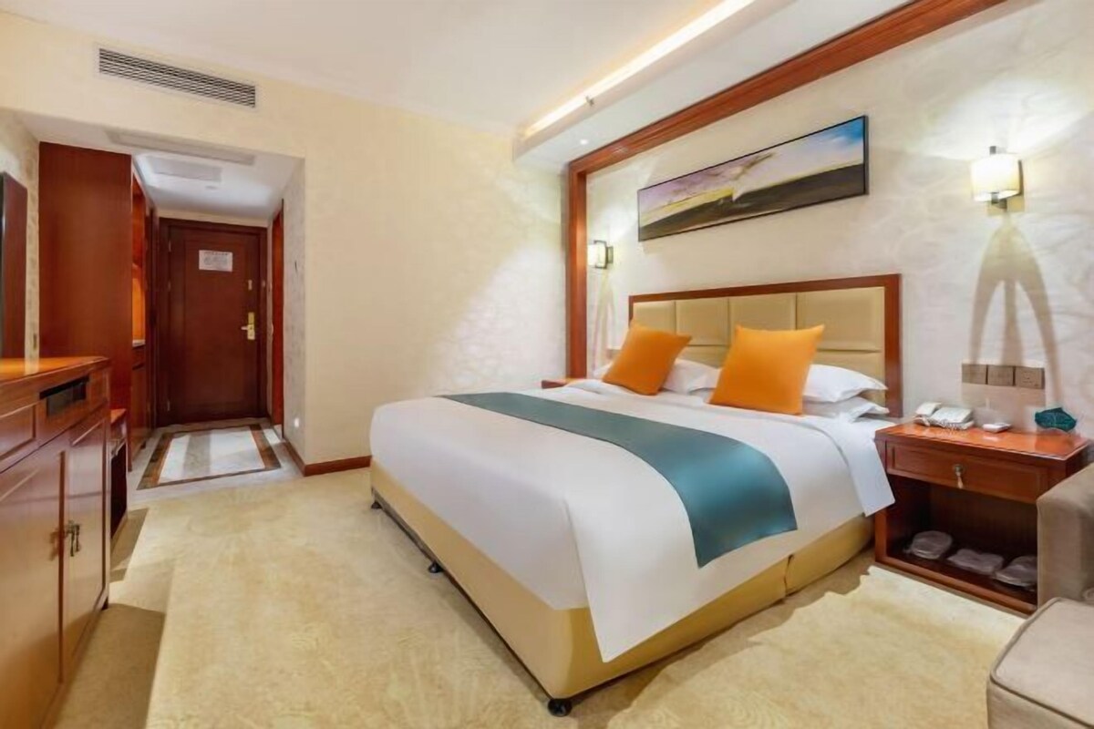 Una habitación de hotel con cama, mesita de noche, lámpara y un cuadro en la pared.