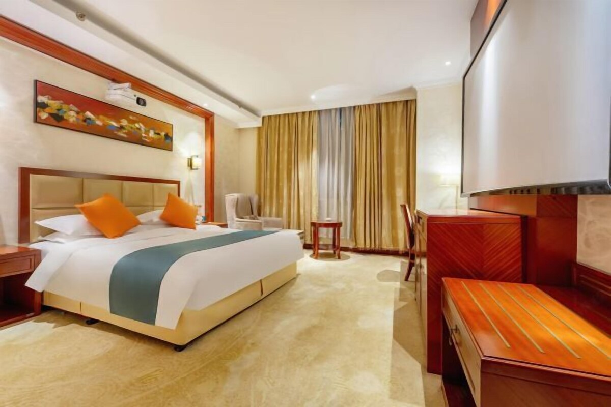 Habitación de hotel con una cama grande, un escritorio, una silla y un televisor.