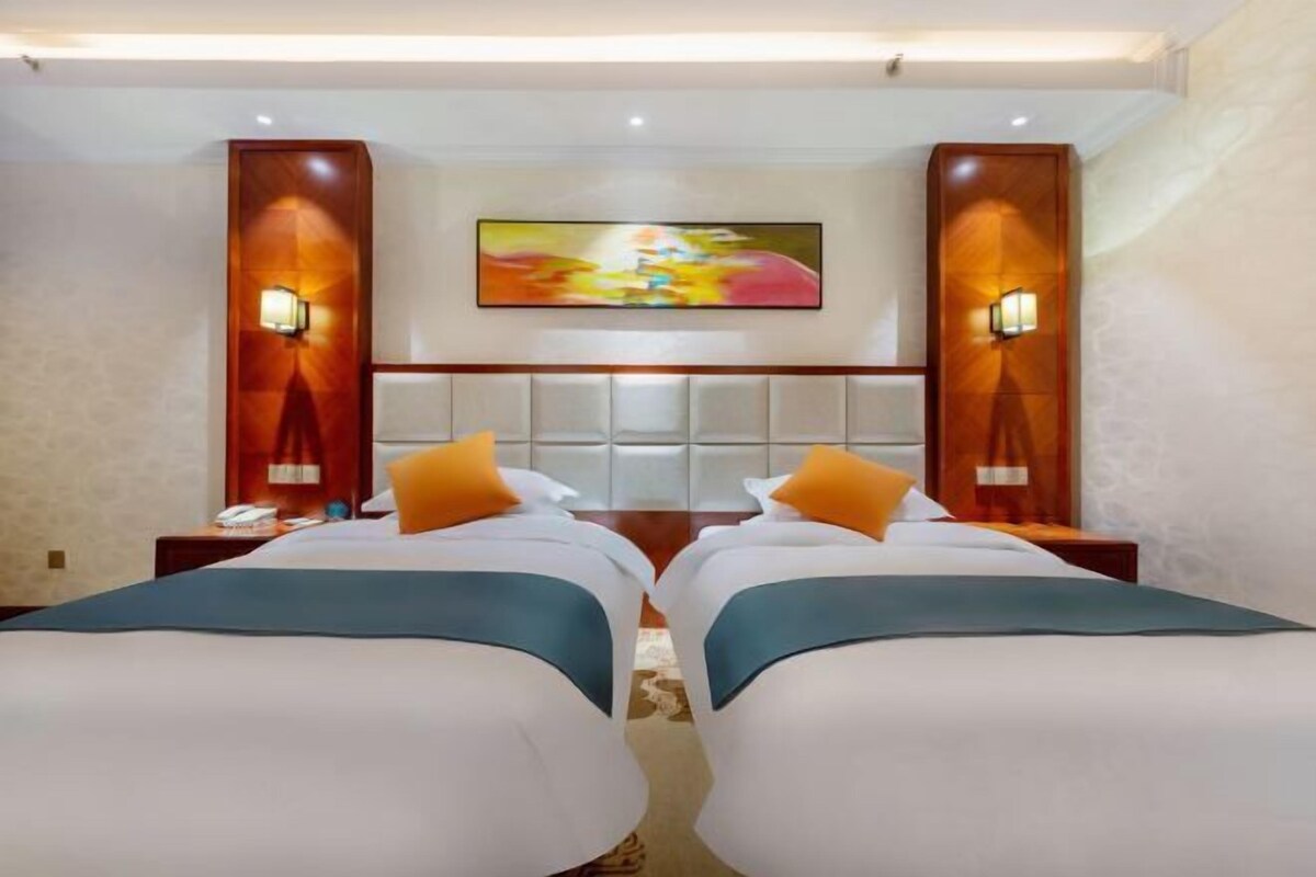Una habitación de hotel con dos camas, una obra de arte grande en la pared y dos mesitas de noche con lámparas.