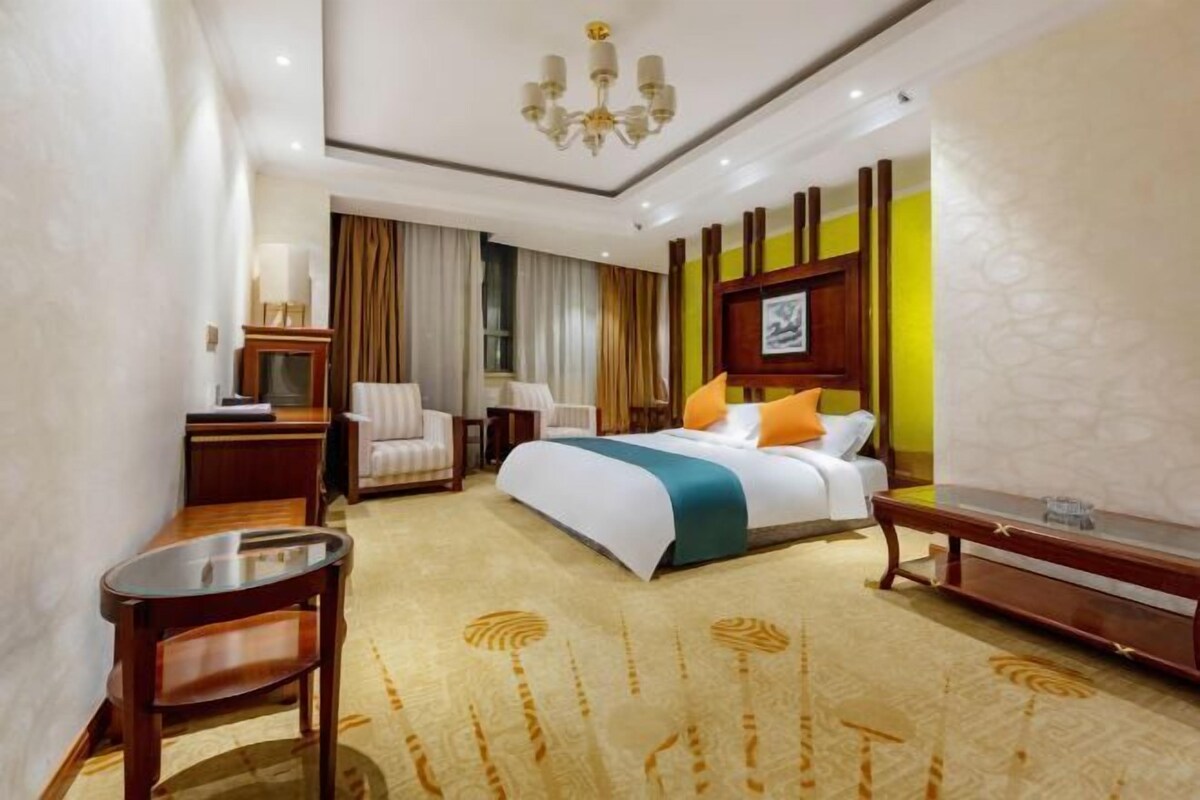 Una habitación de hotel con cama, escritorio, silla, lámpara y candelabro.