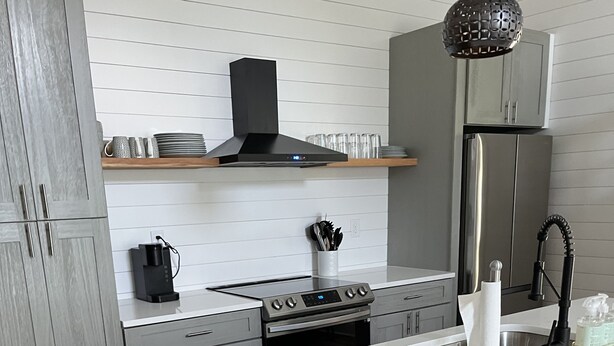 Una cocina moderna con una isla central, electrodomésticos de acero inoxidable y suelo de madera.