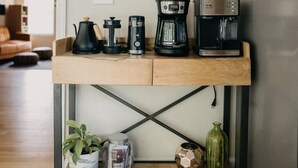 Uma bancada de cozinha com máquinas de café, chaleira e uma planta.