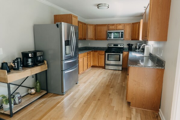 A modern kitchen with wooden cabinets, stainless steel appliances, and a granite countertop.