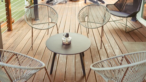 Um deck de madeira com móveis de exterior, incluindo cadeiras e uma mesa, sob uma cobertura.