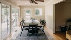 Uma sala de jantar com uma mesa grande, cadeiras pretas e um ventilador de teto.