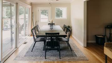 Une salle à manger avec une grande table, des chaises noires et un ventilateur de plafond.