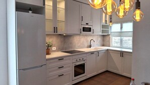 A modern kitchen with white cabinets, a built-in oven, a microwave, and a sink.